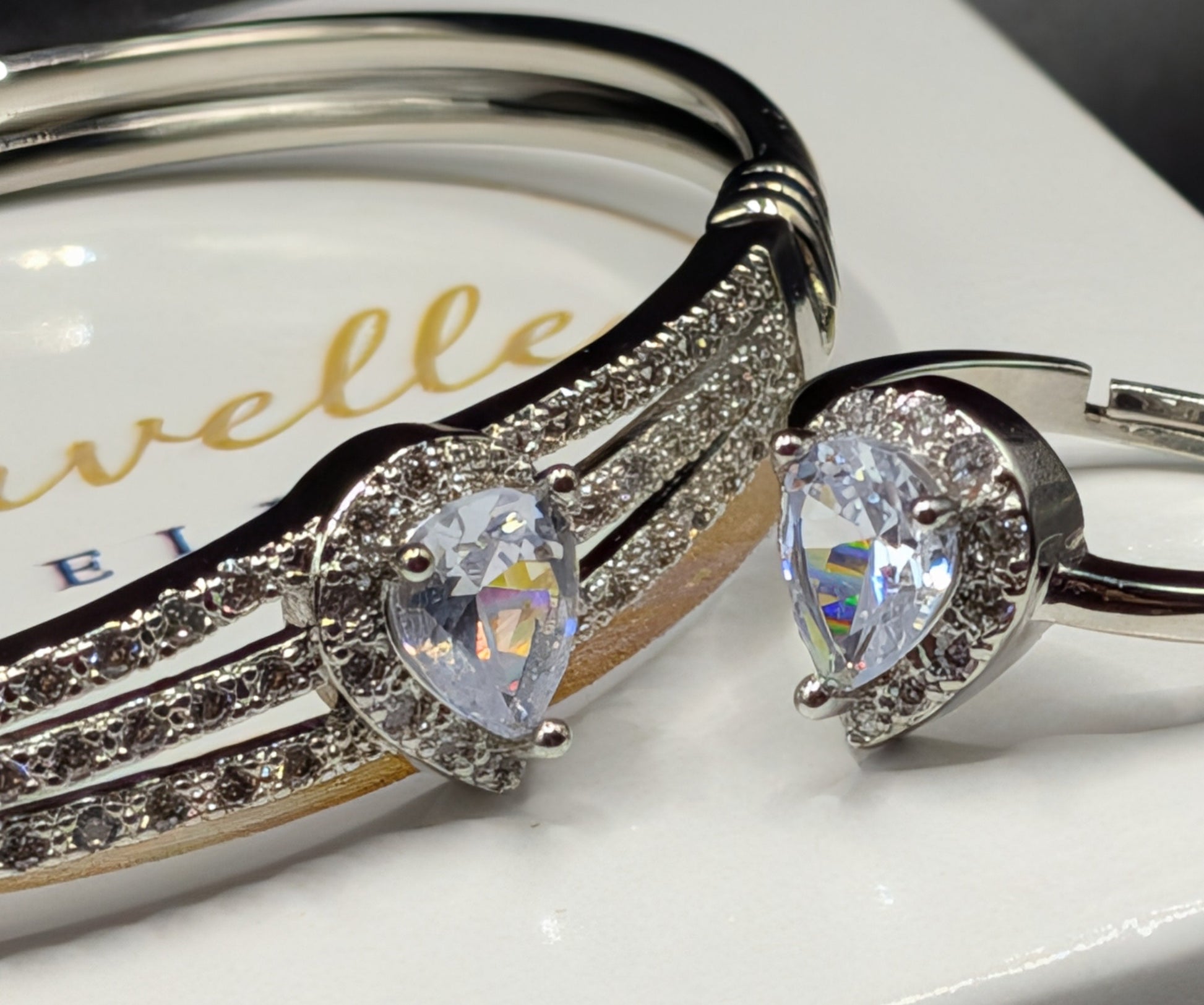 Silver bracelet and ring with tear shaped gemstones on a white surface.