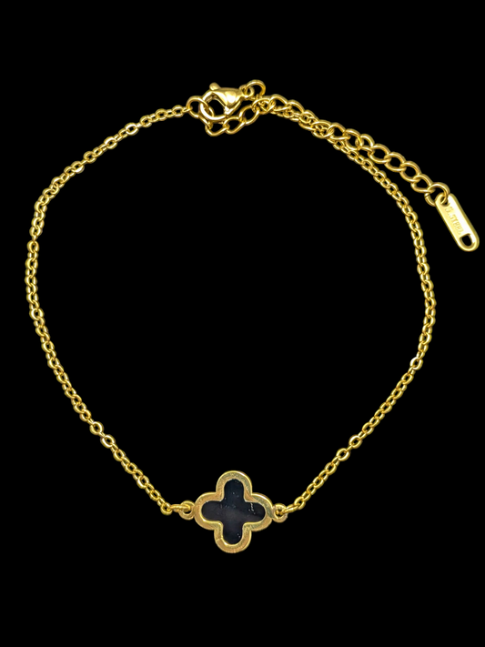 Gold bracelet with a clover-shaped black stone on a black background