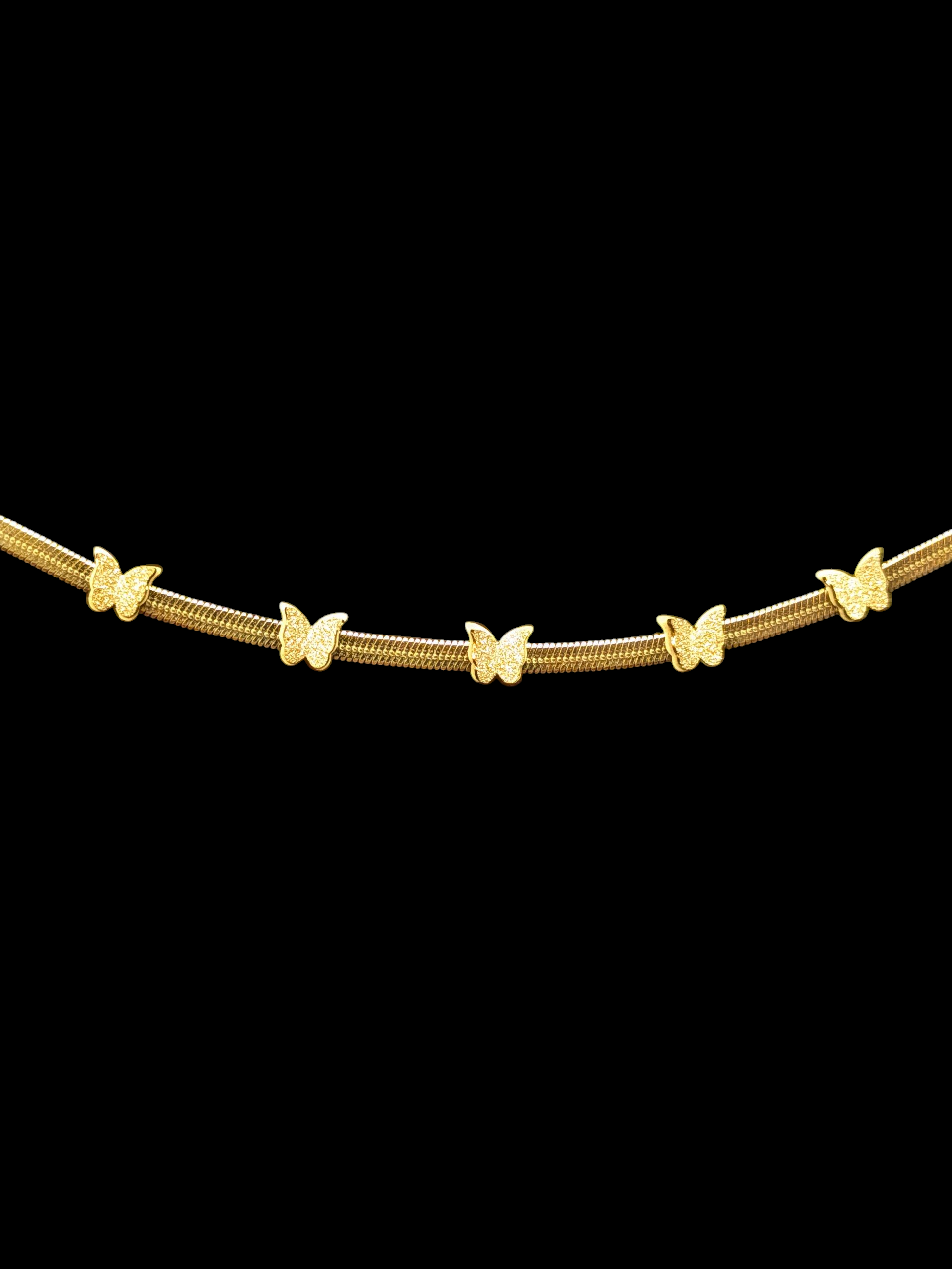 Gold necklace with butterfly pendants on a black background